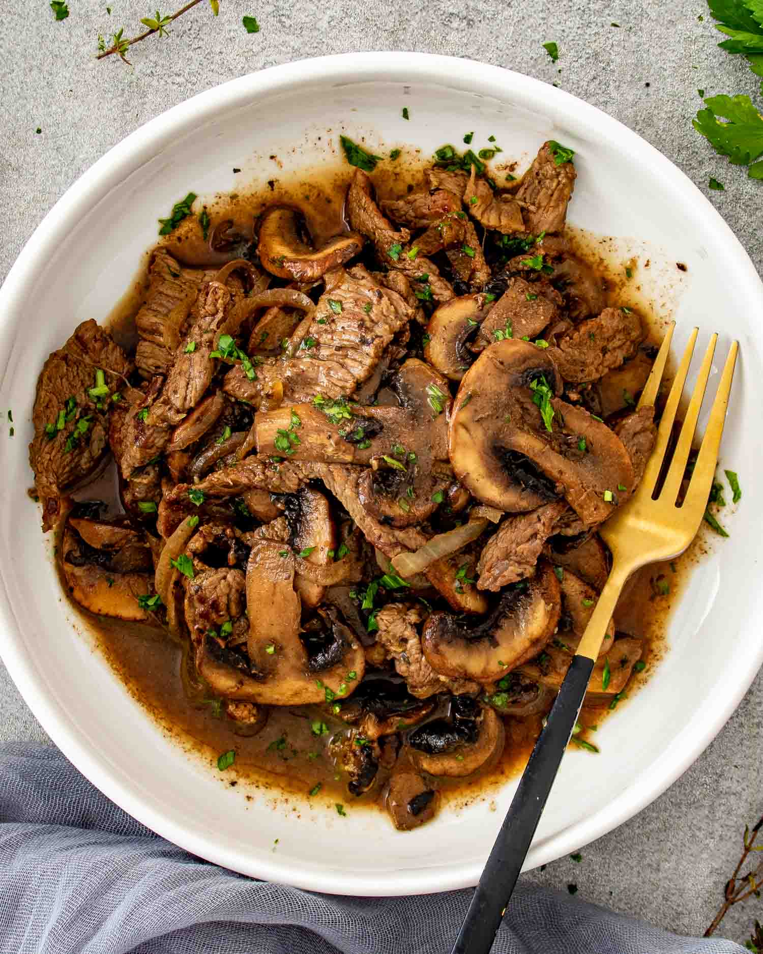 Steak and mushroom skillet plated with sauce spooned over tender beef and mushrooms, finished with chopped parsley.
