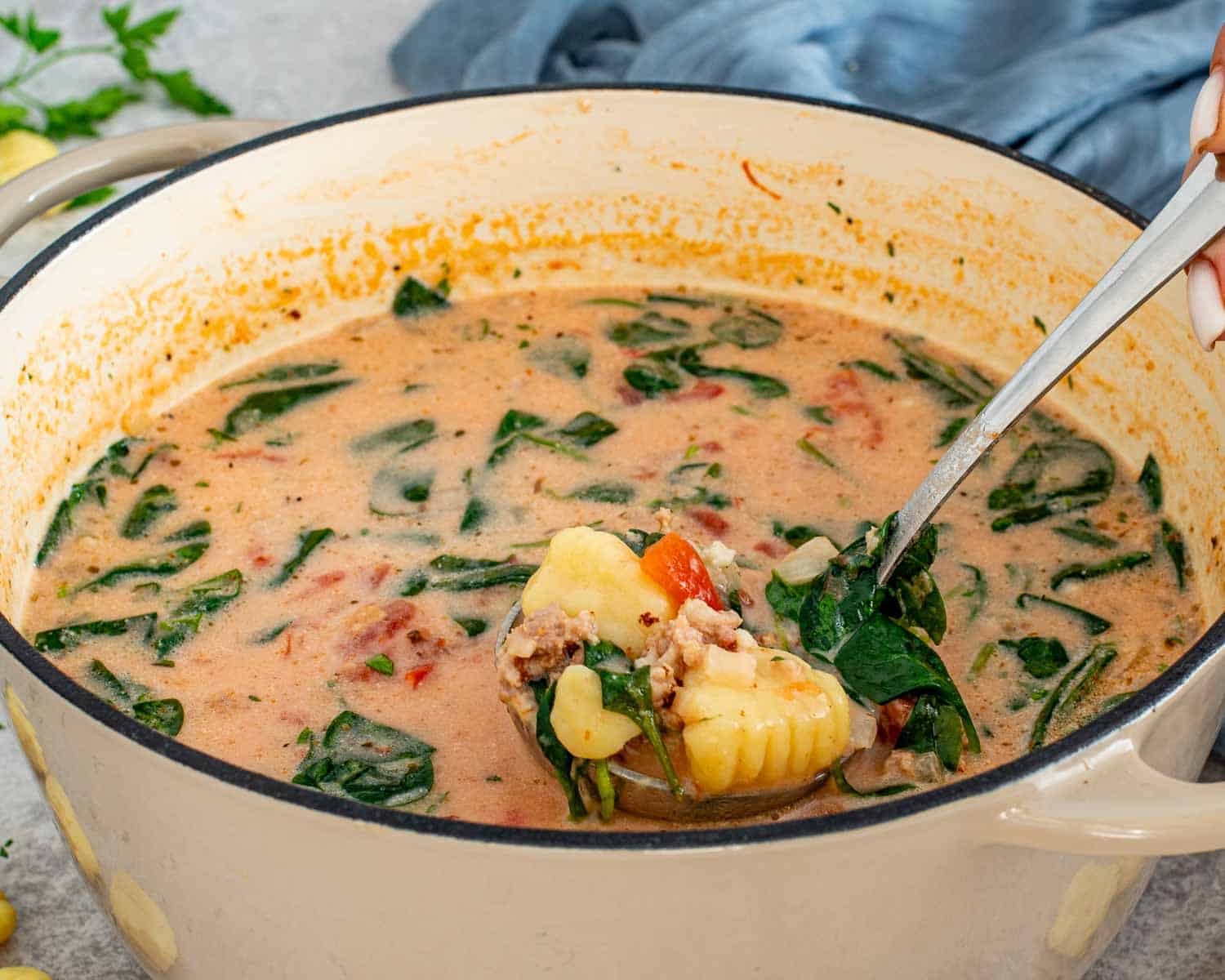 Ladle scooping Tuscan Sausage Gnocchi Soup from pot with gnocchi, sausage, spinach, and rich creamy broth.