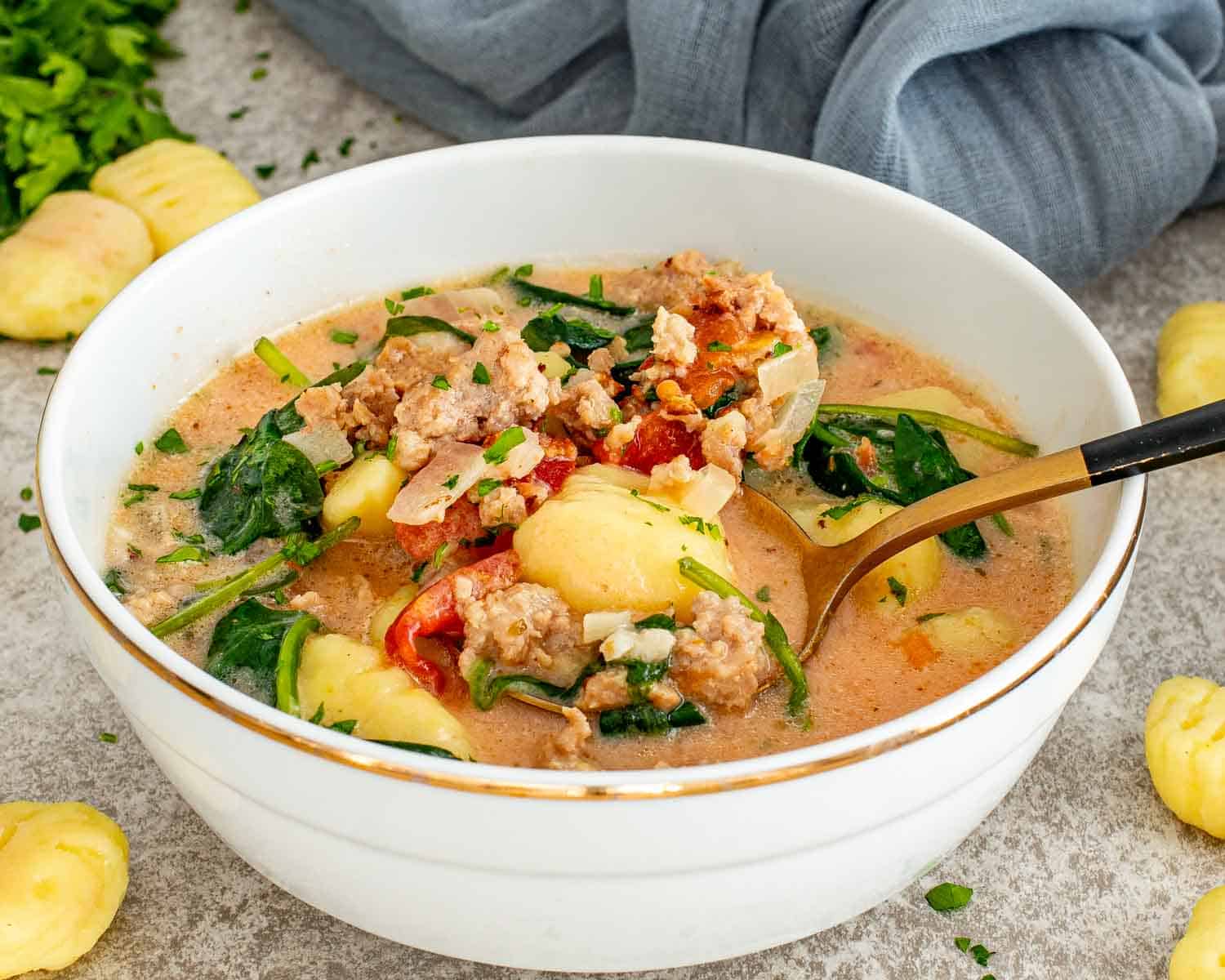 Close up of Tuscan Sausage Gnocchi Soup showing gnocchi, Italian sausage, spinach, and creamy tomato broth.