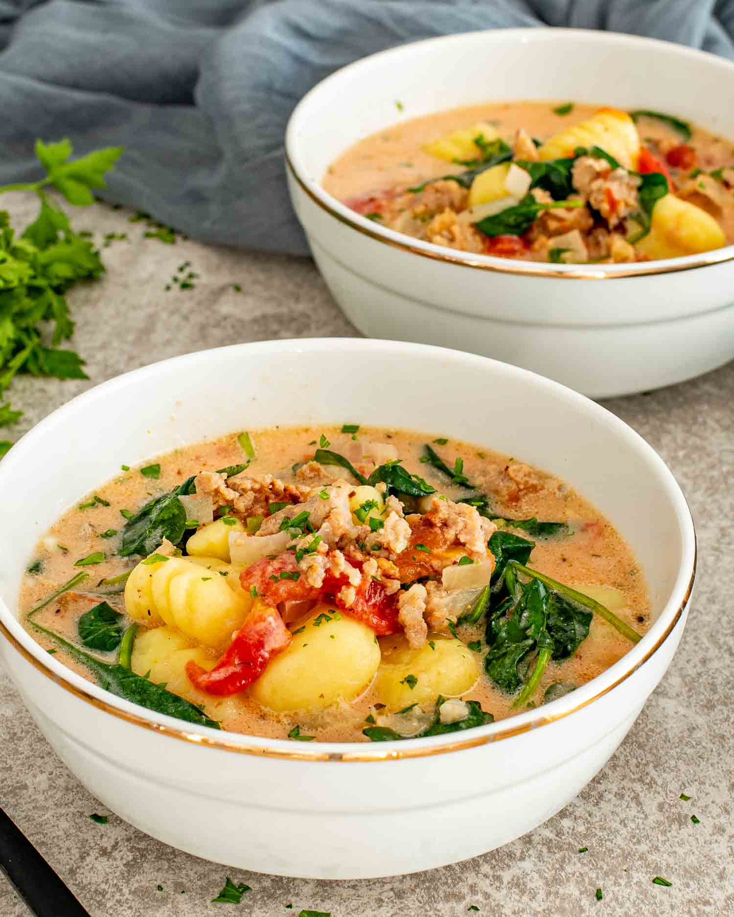 Two bowls of Tuscan Sausage Gnocchi Soup with tender gnocchi, sausage, spinach, and creamy tomato broth.