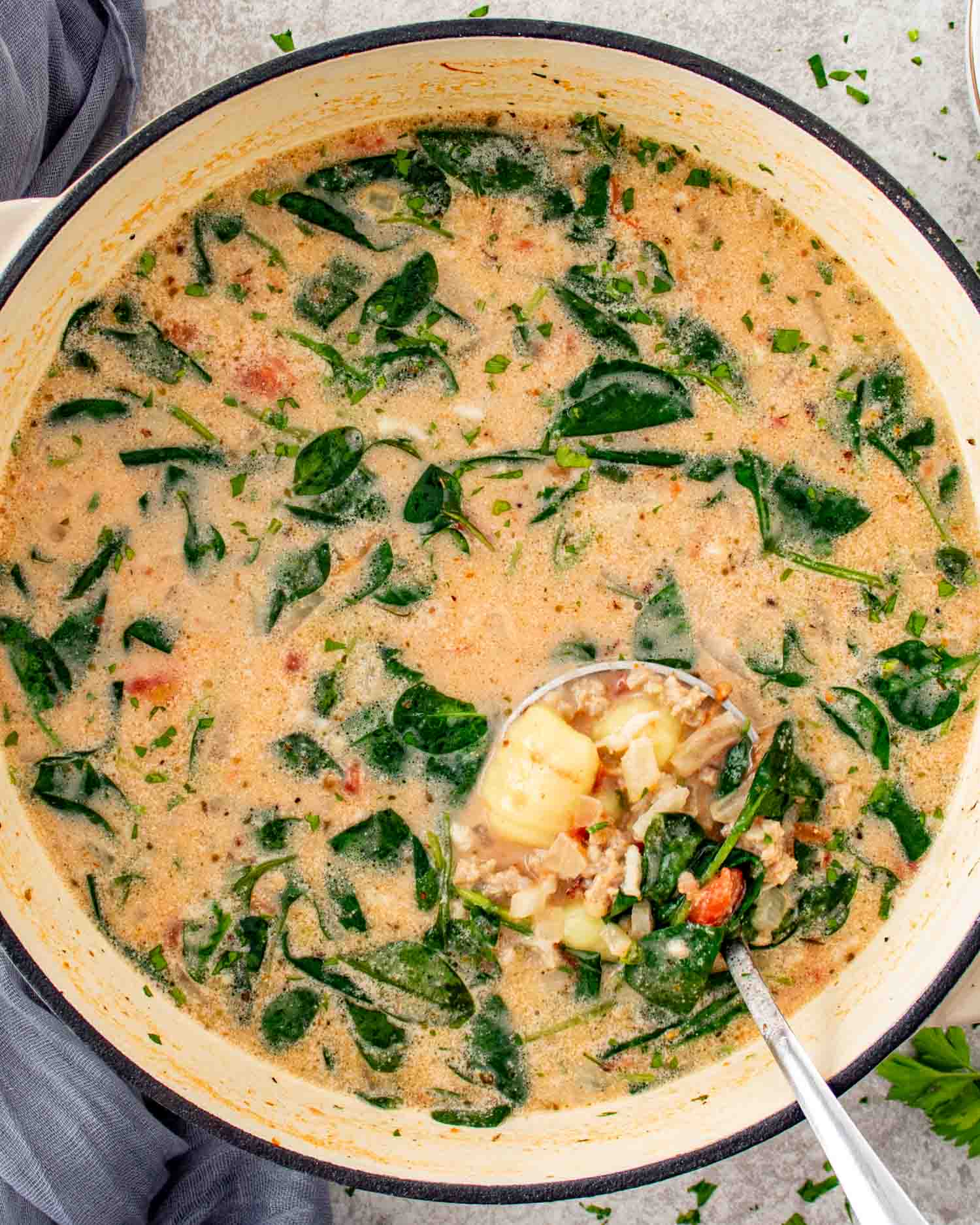 Tuscan Sausage Gnocchi Soup simmering in a Dutch oven with creamy broth, sausage, gnocchi, spinach, and tomatoes.