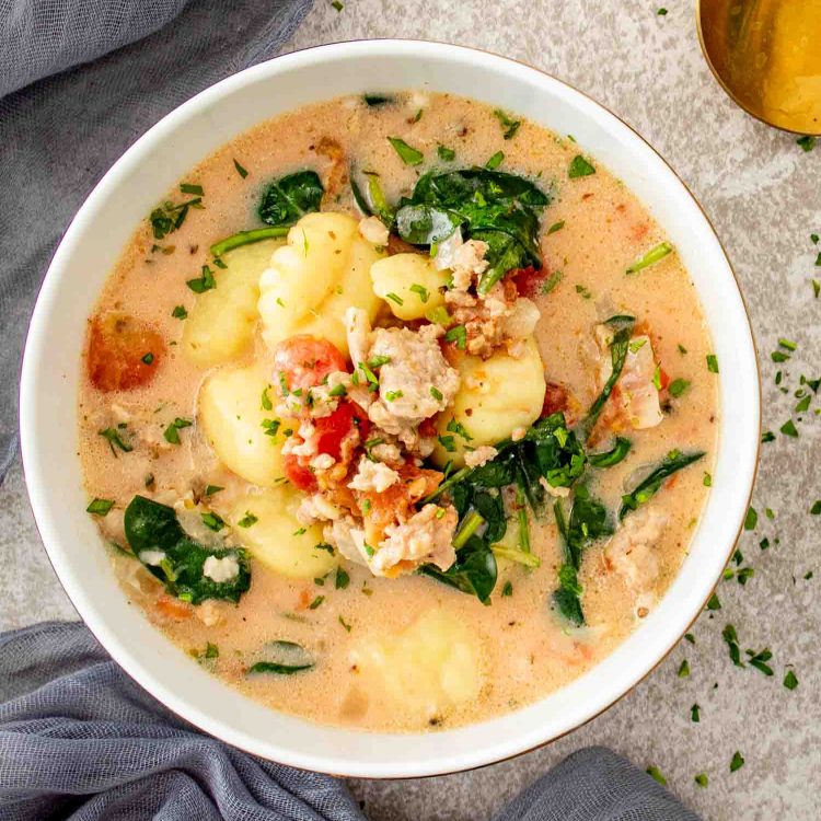 Creamy Tuscan Sausage Gnocchi Soup served in a bowl with Italian sausage, gnocchi, spinach, tomatoes, and Parmesan.