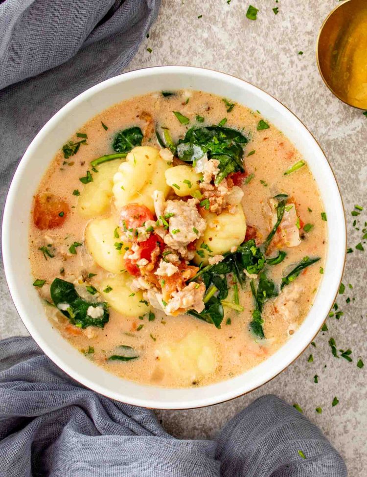 Creamy Tuscan Sausage Gnocchi Soup served in a bowl with Italian sausage, gnocchi, spinach, tomatoes, and Parmesan.