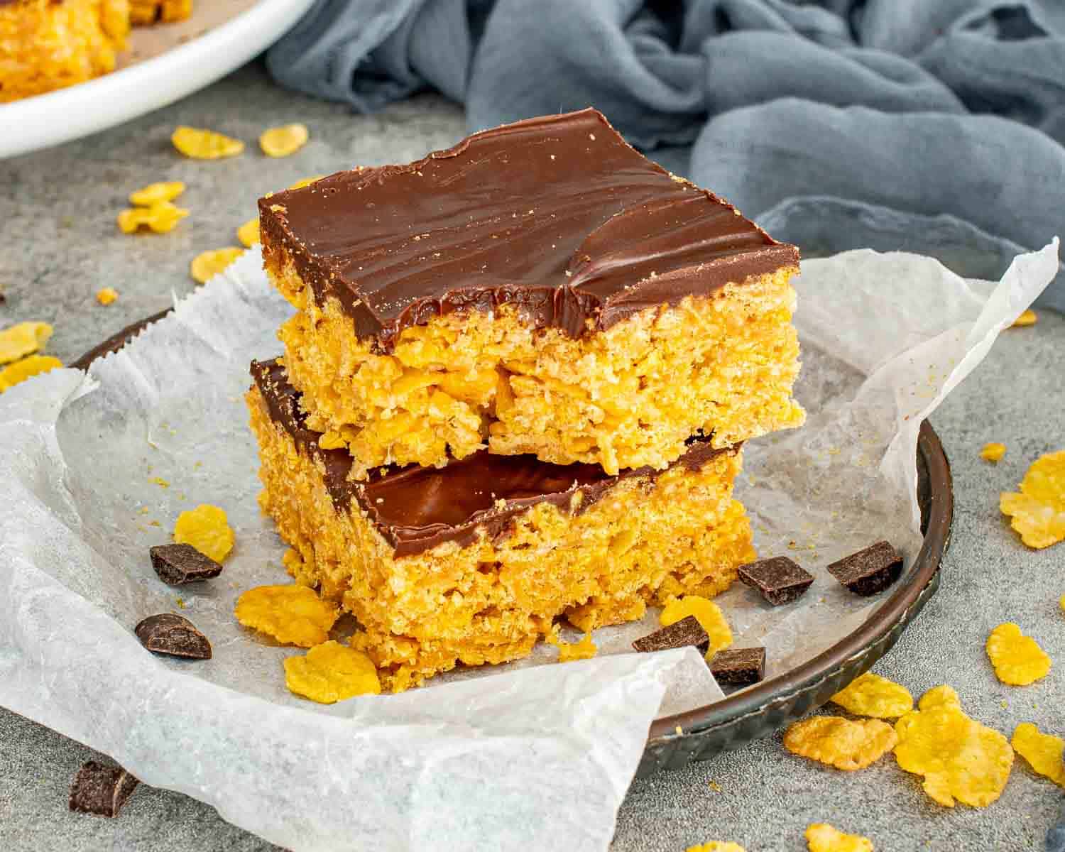 Two thick Butterfinger bars stacked on parchment paper showing crunchy peanut butter cornflake base and glossy chocolate topping.