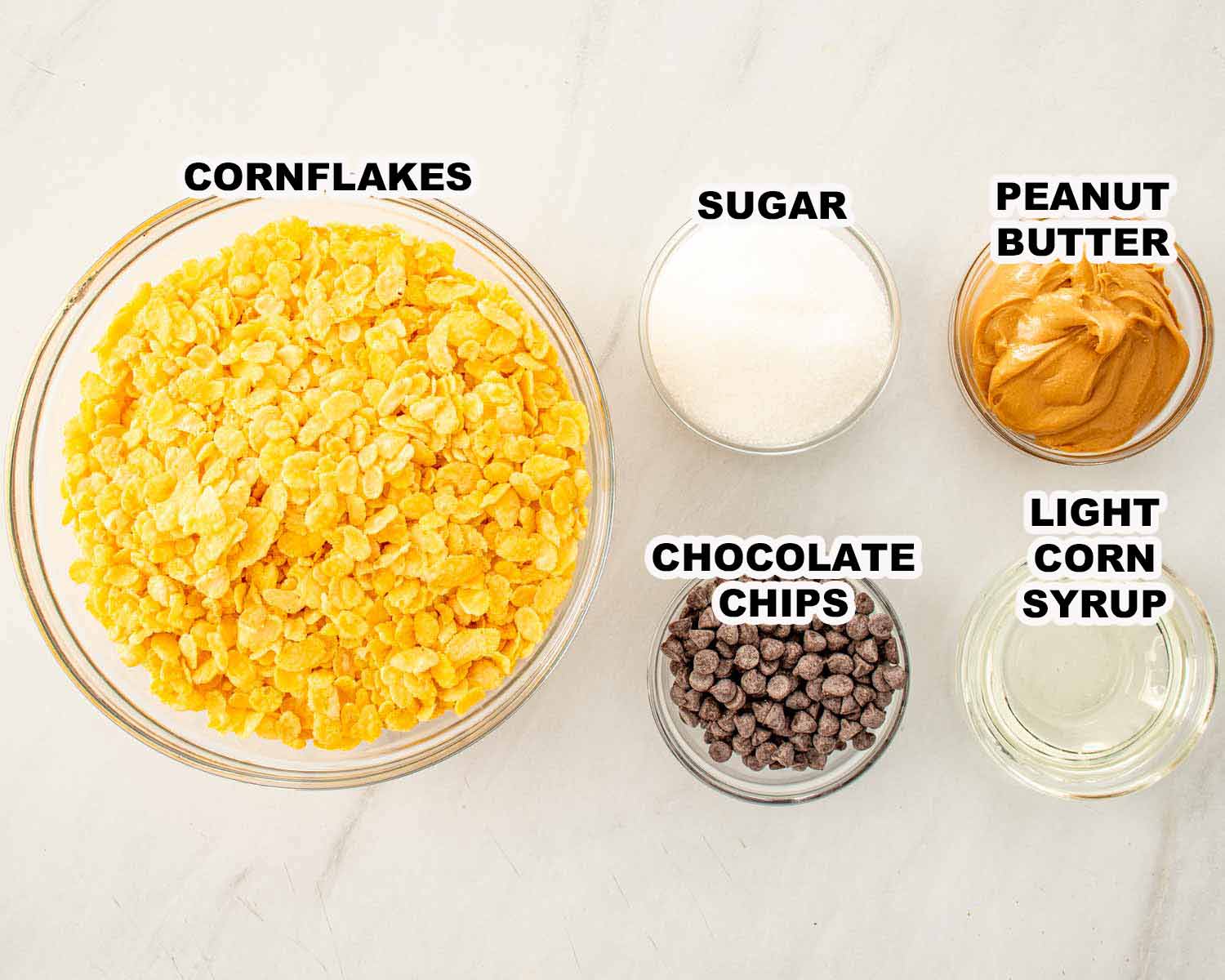 Ingredients for no bake Butterfinger bars including cornflakes cereal, peanut butter, sugar, corn syrup, and chocolate chips.