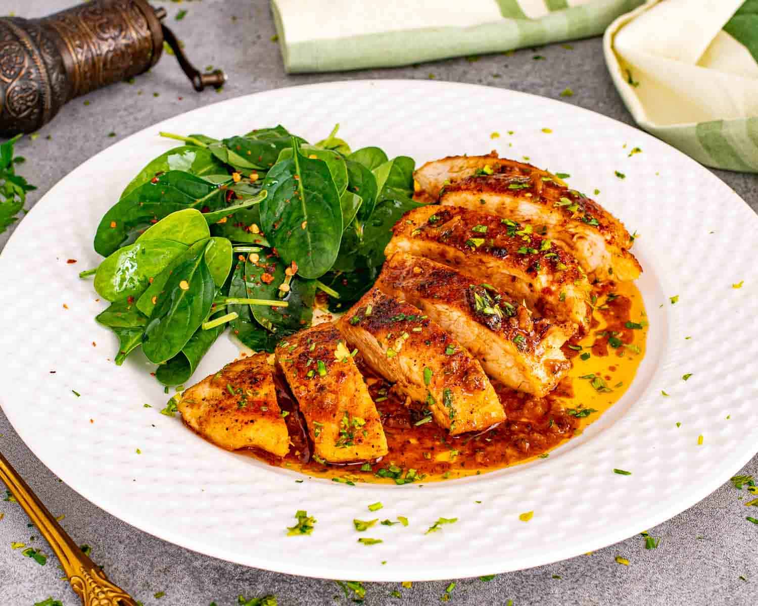 Sliced cowboy butter chicken served on a plate with fresh greens, coated in glossy garlic butter sauce and sprinkled with herbs.