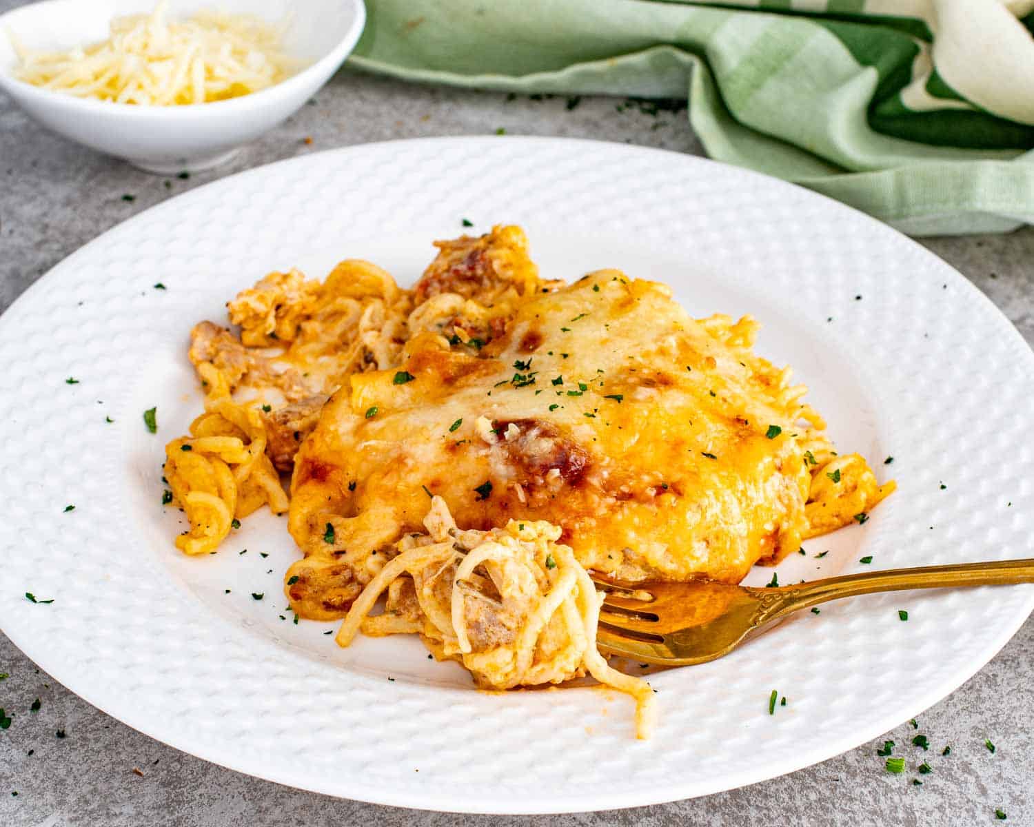 Serving of creamy baked spaghetti on a white plate with fork.