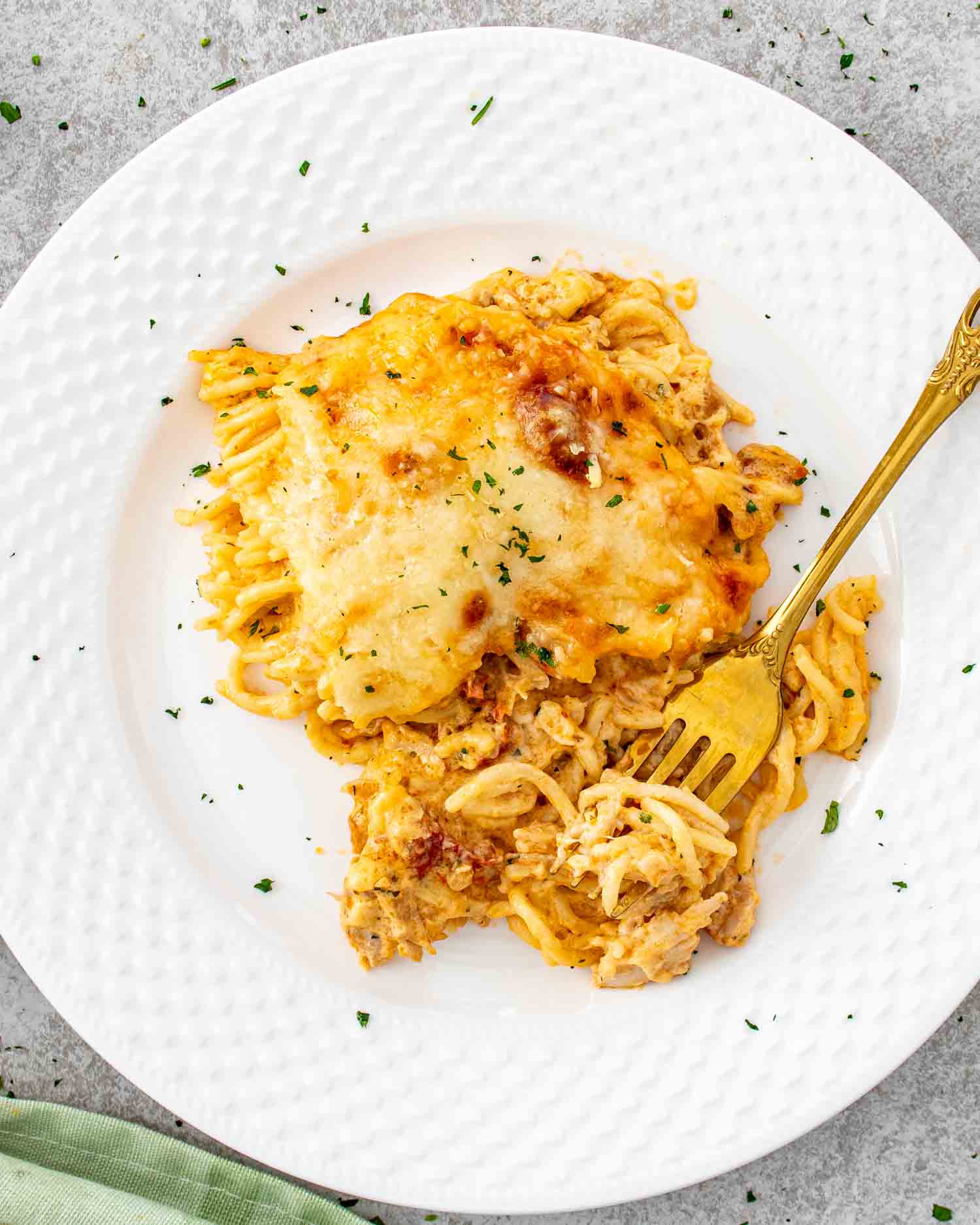 Serving of creamy baked spaghetti on a white plate with fork.