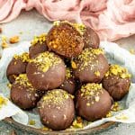 Chocolate covered pistachio date balls with a soft date and pistachio center.