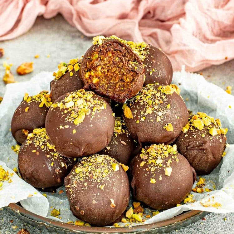 Chocolate covered pistachio date balls with a soft date and pistachio center.
