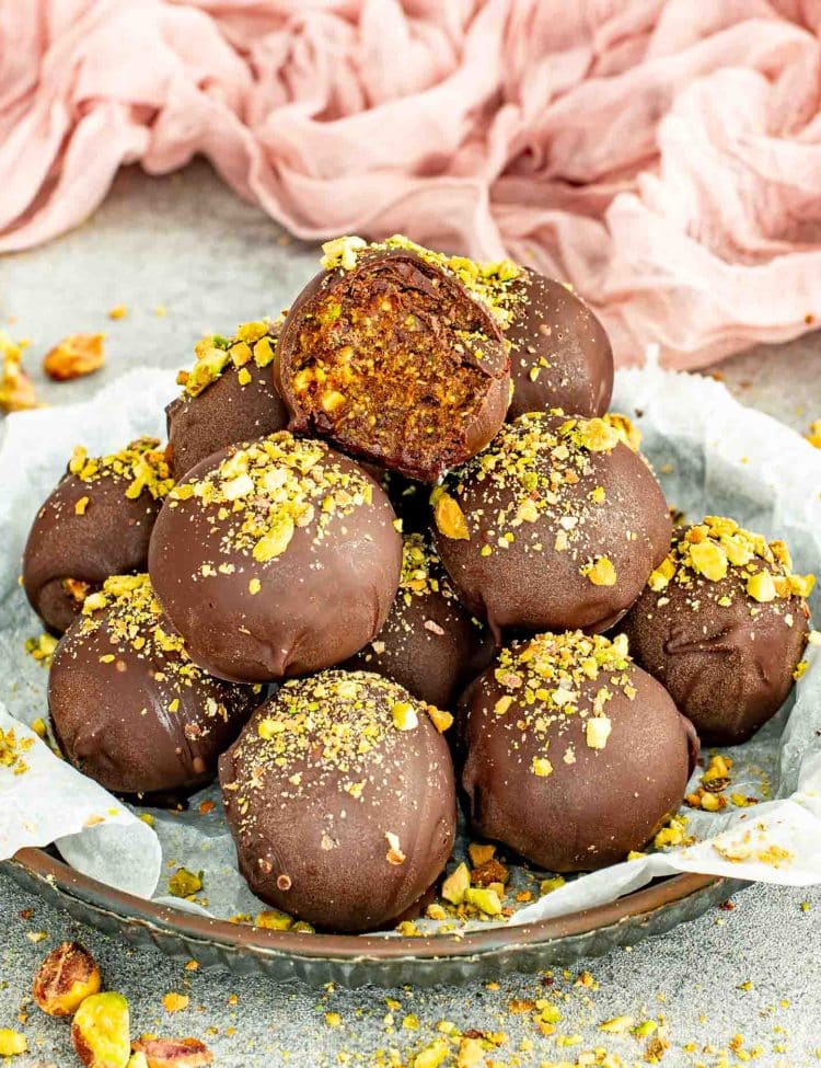 Chocolate covered pistachio date balls with a soft date and pistachio center.