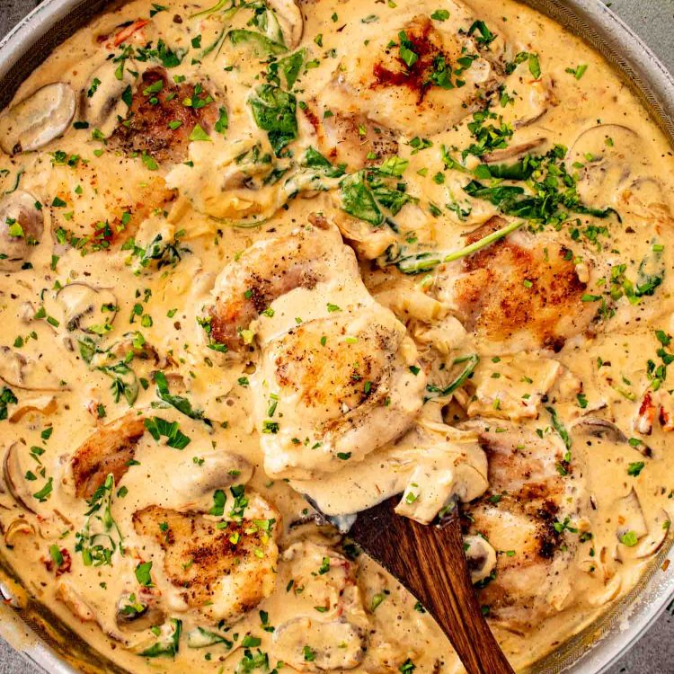 One pan creamy mushroom and sun dried tomato chicken with golden chicken thighs simmered in rich sauce with spinach and mushrooms.