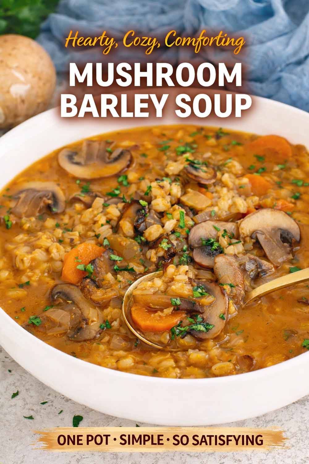 Hearty mushroom barley soup in a white bowl with carrots, herbs, and a rich savory broth, close up view.