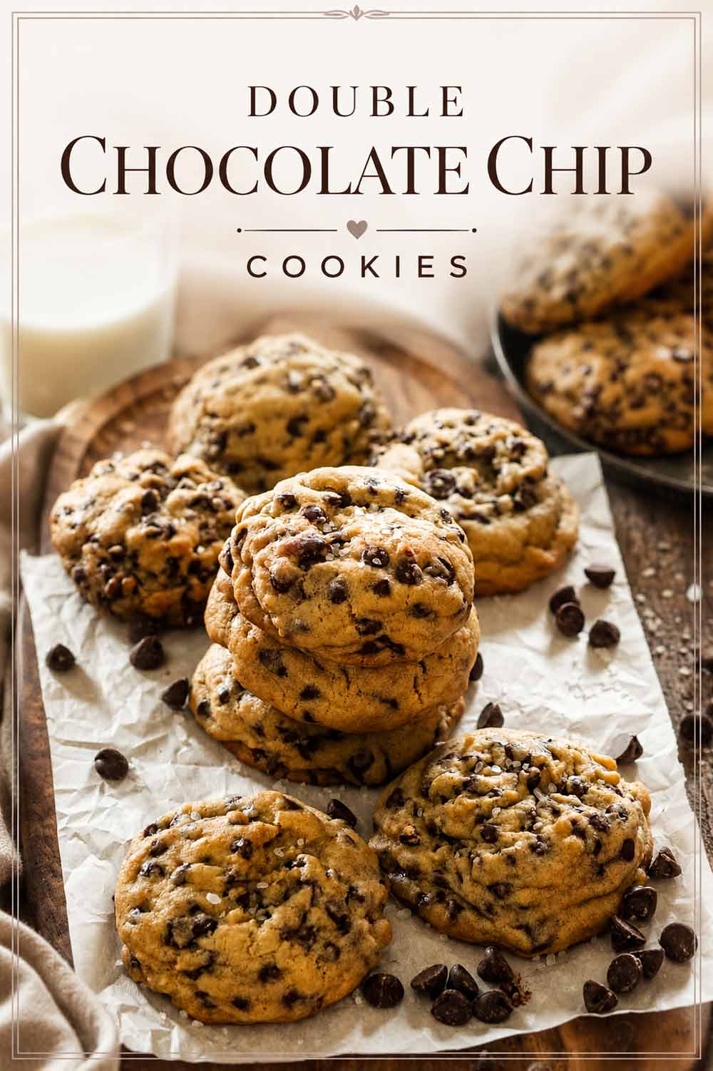 Double Chocolate Chip Cookies stacked on parchment paper on a wood board with a glass of milk in the background, with elegant text overlay reading Double Chocolate Chip Cookies.