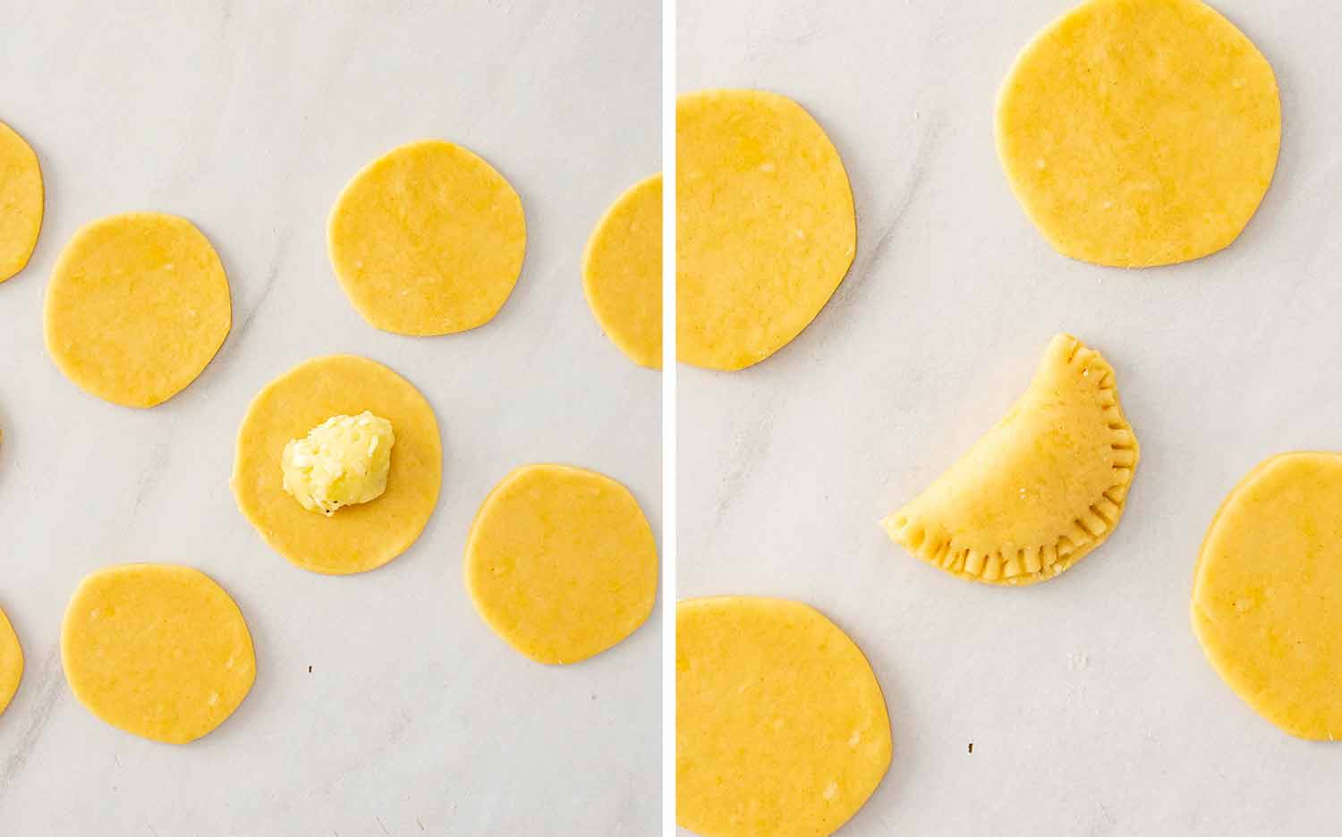 Round pierogi dough circles on a marble surface with potato cheddar filling then one sealed into a half moon shape with crimped edges.