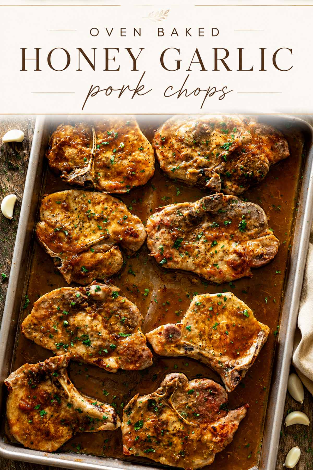 Elegant Pinterest graphic featuring oven baked honey garlic pork chops with a creamy text banner over a rustic sheet pan.