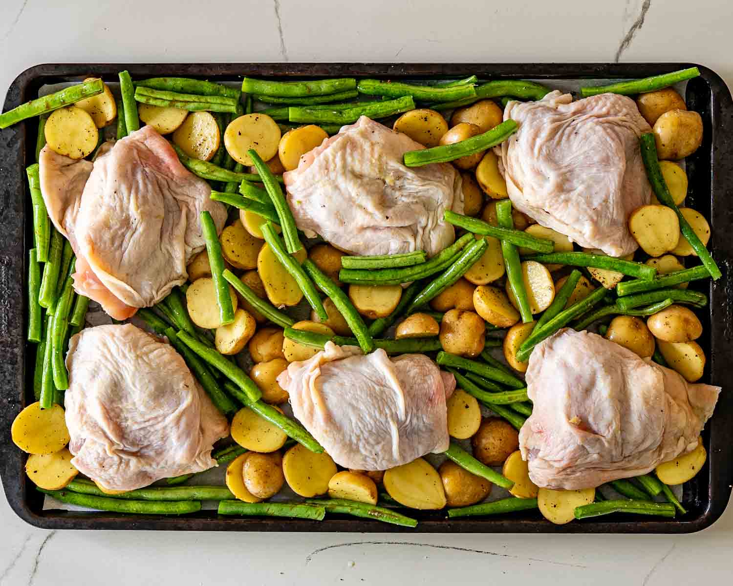 process shots showing how to make parmesan garlic chicken and potatoes sheet pan.