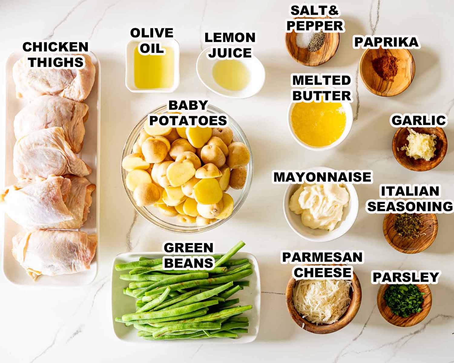 Overhead view of ingredients for Parmesan Garlic Chicken and Potatoes Sheet Pan, neatly arranged and labeled on a countertop.
