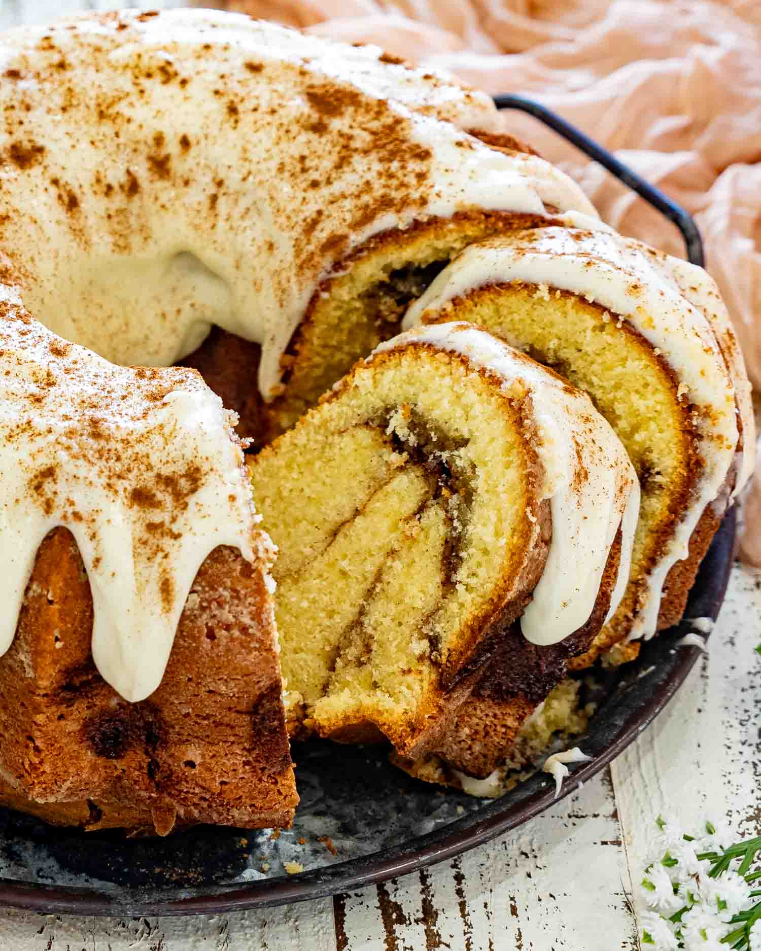 Close-up of cinnamon roll cream cheese pound cake with cream cheese glaze, highlighting the soft buttery crumb and signature cinnamon swirl filling.