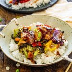 Teriyaki chicken served over fluffy white rice in a rustic handled bowl with roasted vegetables and glossy homemade sauce.