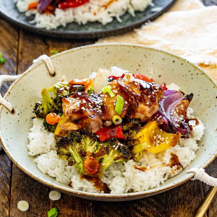 Teriyaki chicken served over fluffy white rice in a rustic handled bowl with roasted vegetables and glossy homemade sauce.