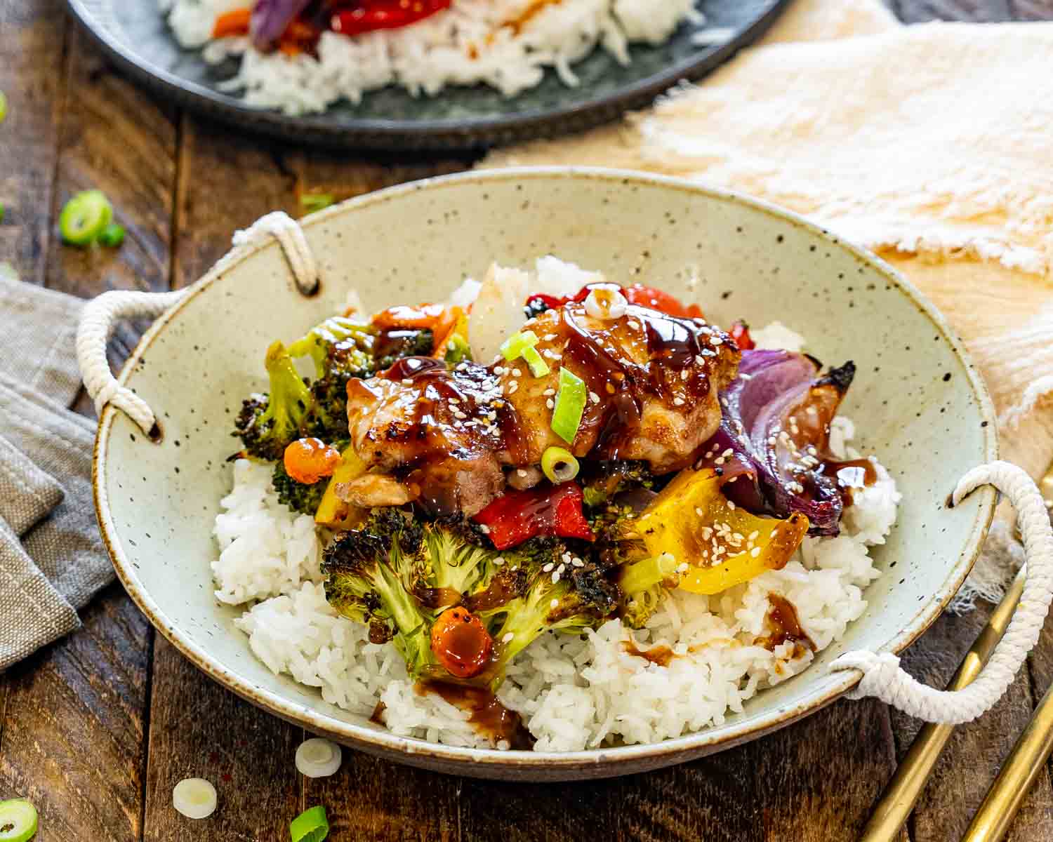 Teriyaki chicken served over fluffy white rice in a rustic handled bowl with roasted vegetables and glossy homemade sauce.