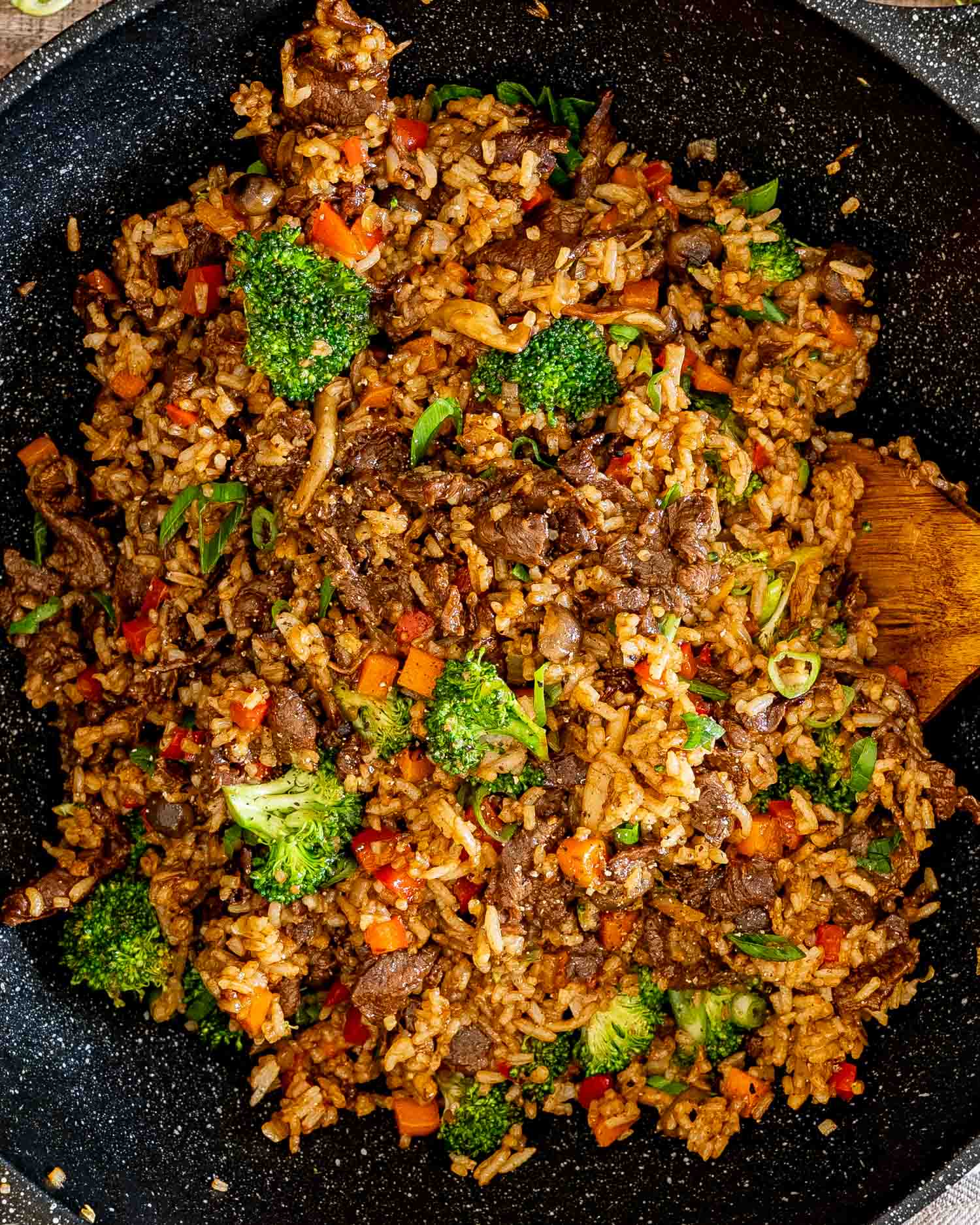 Overhead view of sticky beef fried rice in a skillet filled with juicy beef, broccoli, mushrooms, peppers, carrots, and rice.
