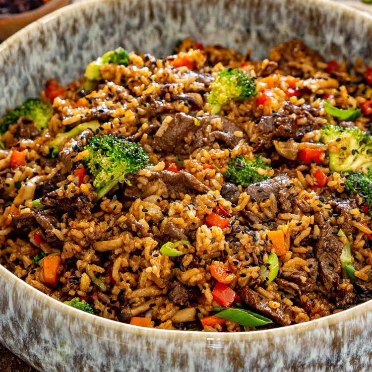 Close-up of sticky beef fried rice packed with tender beef, crisp broccoli, mushrooms, peppers, carrots, and savory seasoned rice.