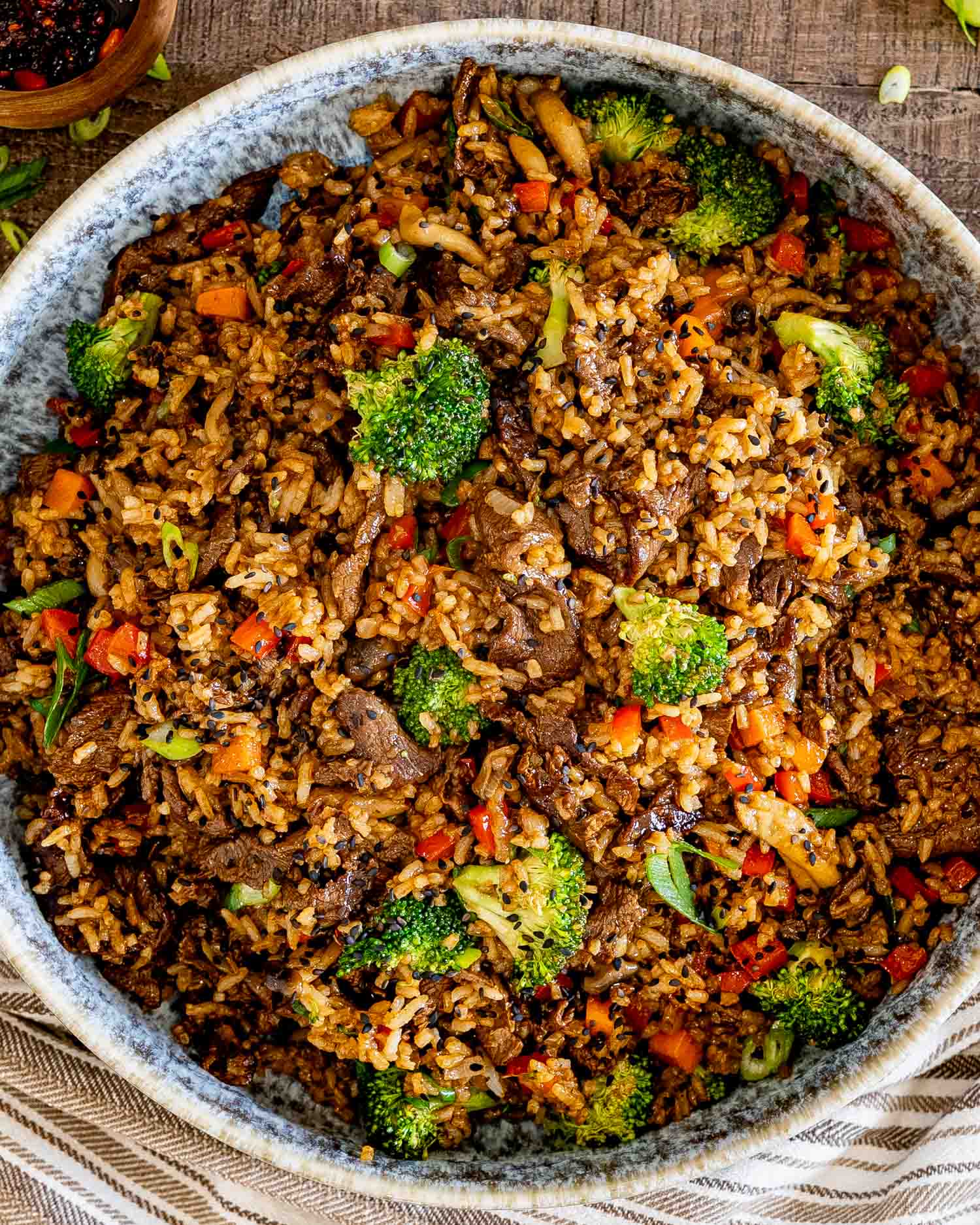Overhead view of sticky beef fried rice loaded with juicy beef, broccoli, mushrooms, peppers, carrots, and fluffy seasoned rice.