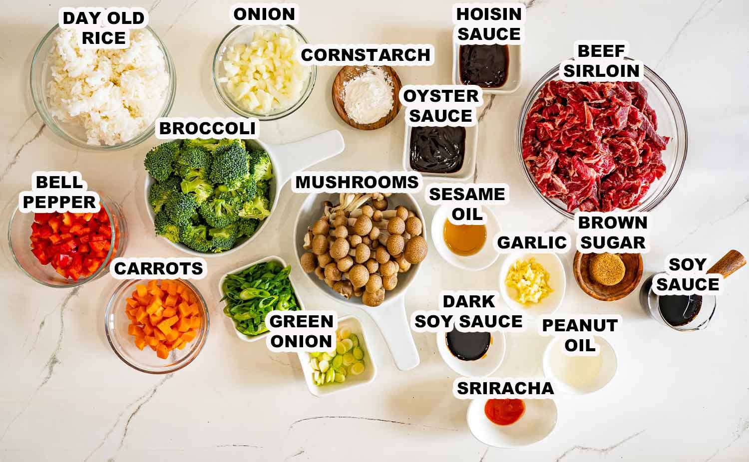 Ingredients for sticky beef fried rice including sliced beef, day-old rice, broccoli, mushrooms, sauces, vegetables, garlic, and seasonings neatly arranged.