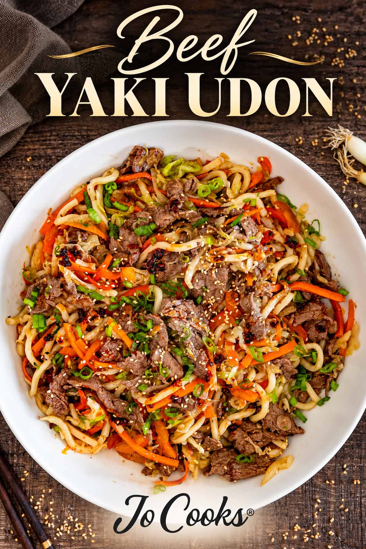 Beef yaki udon in a white bowl on dark wood, with cream recipe title and Jo Cooks logo.