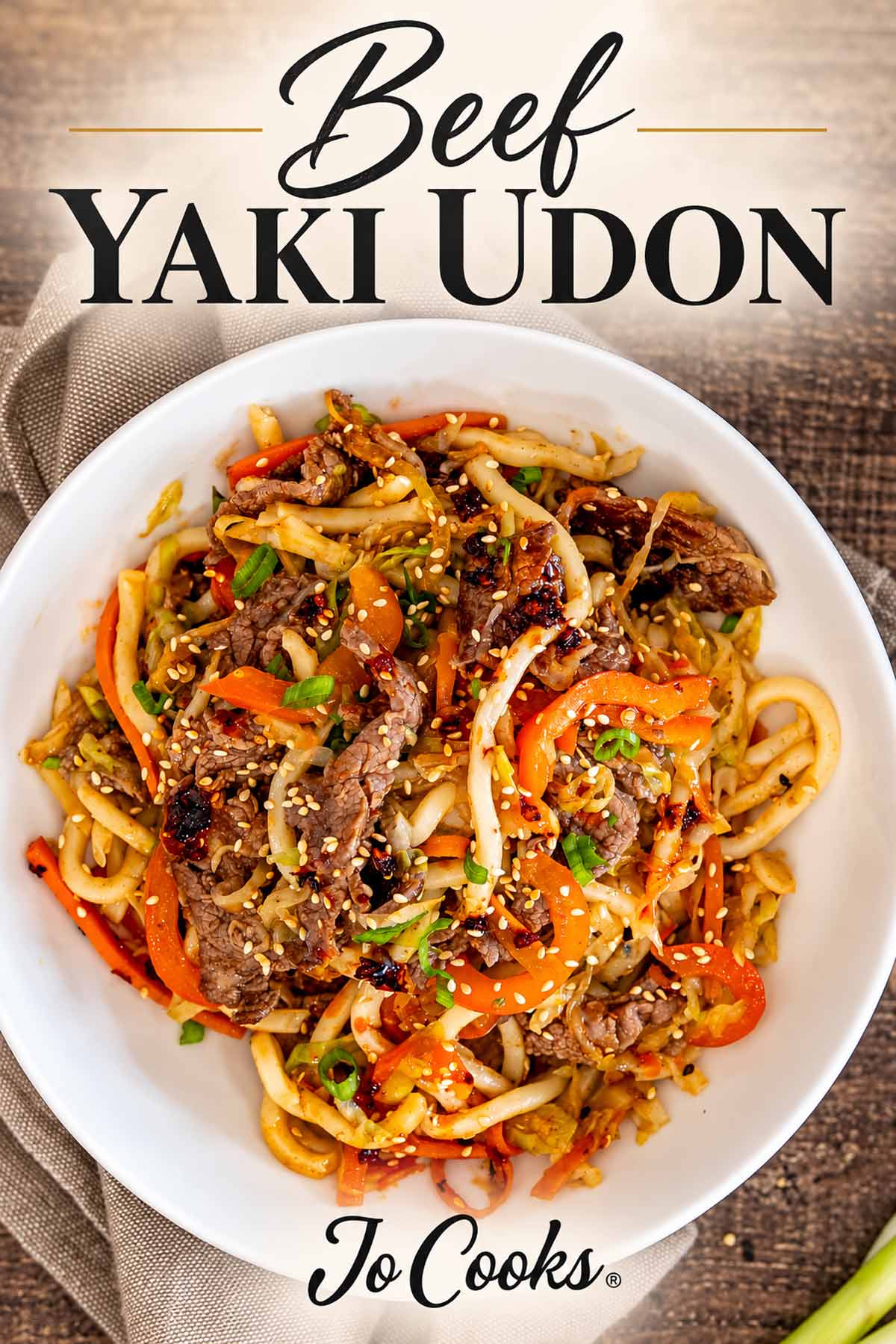 White bowl of beef yaki udon with sesame seeds, black recipe title above, and Jo Cooks logo below.