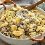 Creamy cheesesteak tortellini with tender steak, mushrooms, and peppers served in a large white handled casserole dish.