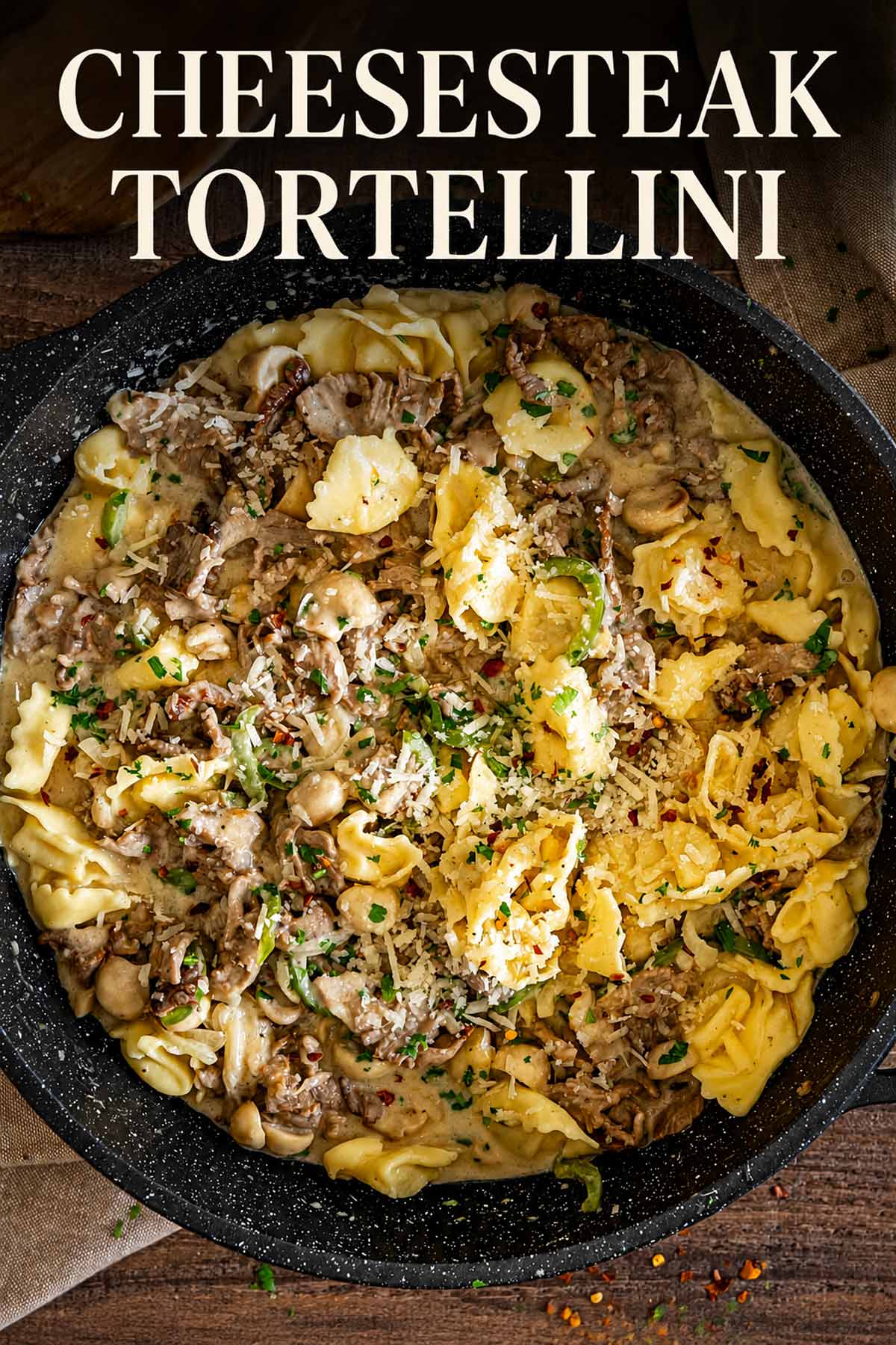 Pinterest image of cheesesteak tortellini with steak, mushrooms, peppers, Parmesan, and parsley in a creamy cheese sauce.