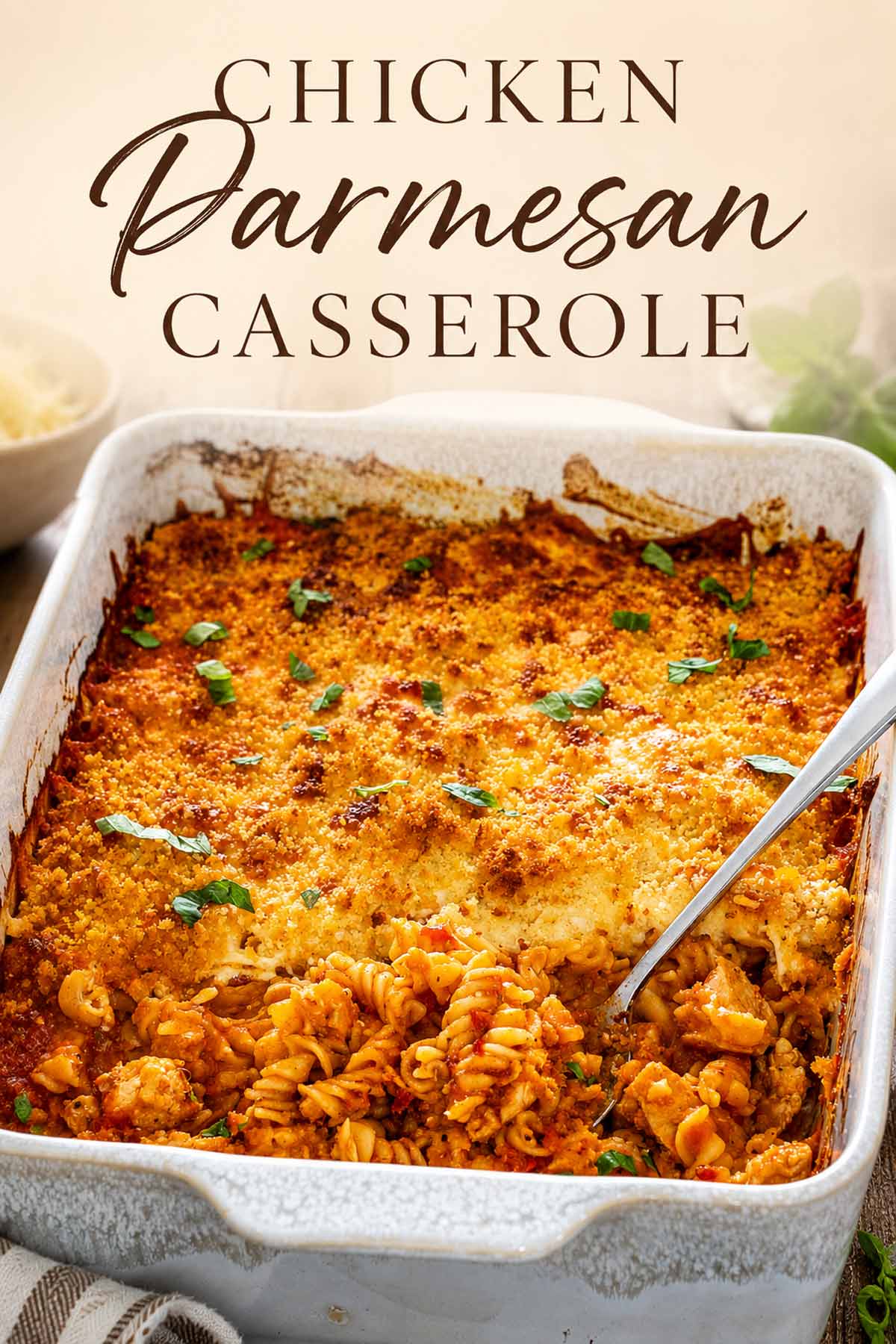 Pinterest graphic featuring golden chicken Parmesan casserole with rotini, marinara, melted cheese, crisp breadcrumbs, and fresh basil.