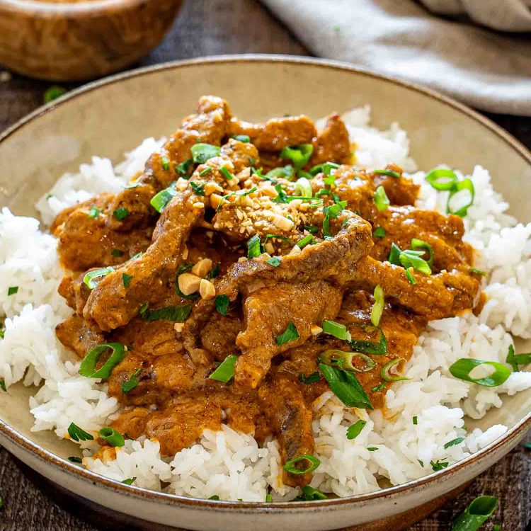 Tender curried beef strips coated in creamy peanut sauce over white rice with chopped peanuts and scallions.
